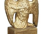 golden statue of a bird with a crown on top of a wooden post