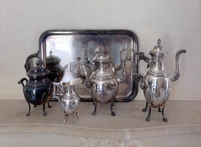 cinq théières en argent et un plateau posés sur une table