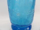 a blue glass vase with writing on it sitting on a table