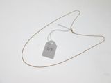 a tag that is attached to a necklace on a white surface