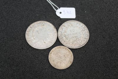 three silver coins and a tag on a black surface