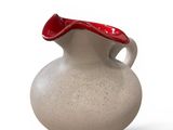 a white vase with a red handle sitting on a white surface