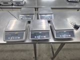 cinq balances électroniques posées sur une table dans une pièce