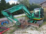 a green excavator that is sitting in the dirt