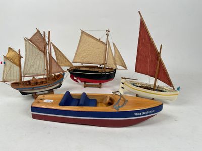 four small wooden boats with sails on a white surface