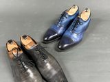 two pairs of men ' s shoes on a grey surface