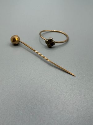 deux bagues en or et une paire de boucles d'oreilles posées sur une surface grise