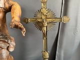 a statue of a man holding a cross next to a candle