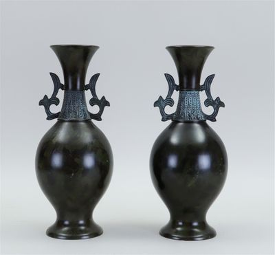 pair of black vases sitting on top of each other on a white surface
