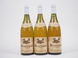 trois bouteilles de vin posées les unes à côté des autres sur une surface blanche
