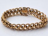 gros plan d'un bracelet en or sur une surface blanche