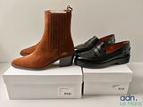 deux paires de chaussures marron et noires posées sur des cartons