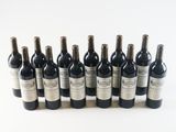 six bottles of wine are lined up in a row on a white surface