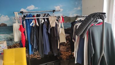 a rack of clothes in front of a window with a view of the ocean