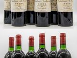 six bottles of red wine are lined up on a white surface