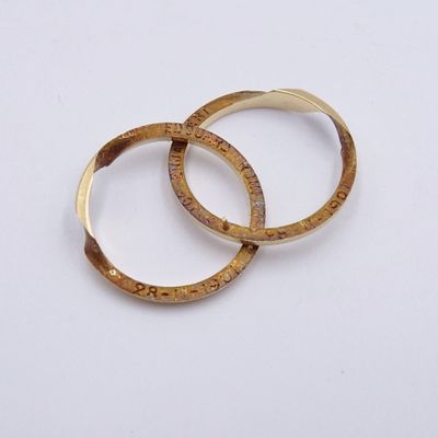two gold rings on a white surface with a white background