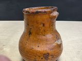 a brown vase sitting on a table with a black background