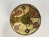 a decorative bowl with a bird on it on a white surface