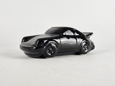 une petite voiture noire posée sur une surface blanche