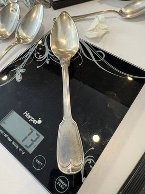 des cuillères et des cuillères à soupe posées sur une balance, sur un plan de travail de cuisine