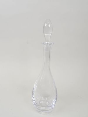 une carafe en verre transparent posée sur une surface blanche, avec un fond blanc
