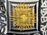 a black and white scarf with a gold sun on it