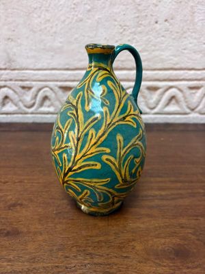 un vase vert et doré posé sur une table en bois
