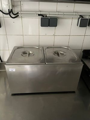 plan de travail en acier inoxydable avec deux bacs à eau chaude dans une cuisine professionnelle