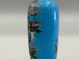 a blue vase with a bird and flowers on it