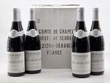 trois bouteilles de vin rouge sont posées devant une boîte