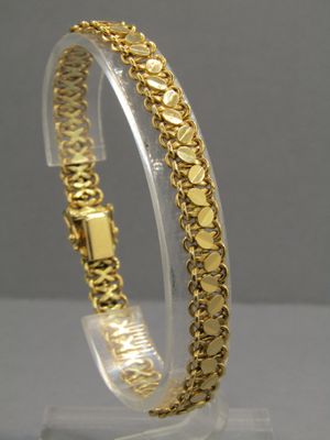 un gros plan d'un bracelet en or posé sur un socle transparent