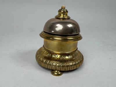 a silver and gold bell sitting on top of a white table