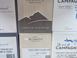 Plusieurs cartons de vin sont empilés sur une table dans une pièce.