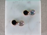 une paire de boucles d'oreilles noires et blanches posées sur une dalle de marbre