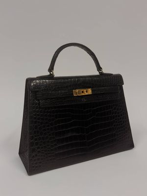 a black crocodile skin handbag on a white background