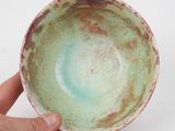 a person holding a bowl in their hand on a white surface