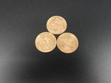 three gold coins sitting on top of each other on a black surface