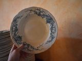 a person that is holding a plate in front of a stack of plates