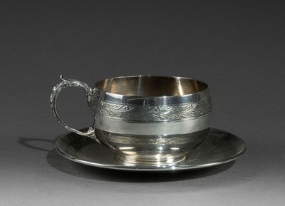 une tasse et une soucoupe anciennes en argent, posées sur un plateau en argent