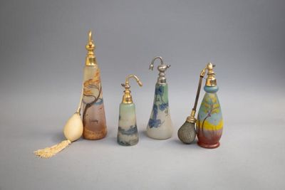 Plusieurs bouteilles en verre de différentes couleurs sont alignées sur une surface grise.