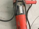 une perceuse rouge et noire posée par terre à côté de quelques fils électriques