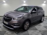 L'Opel grise est garée dans une grande pièce au sol carrelé en damier.