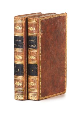two old books are stacked on top of each other on a white surface