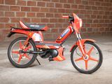 a small red motorcycle parked in front of a brick wall