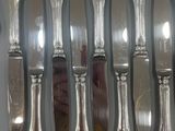 a lot of silver spoons and knives on the table
