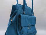 the blue handbag is sitting on a white surface with a gray background