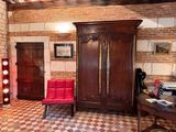 an image of a living room with a red chair and a wooden armoire