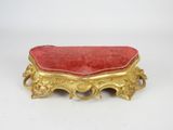 an old gold and red bench with a red cushion on it