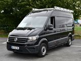 une camionnette noire garée sur un parking, avec des arbres en arrière-plan