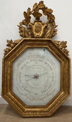 une vieille horloge avec un cadre doré et un cadran posée sur une table en bois